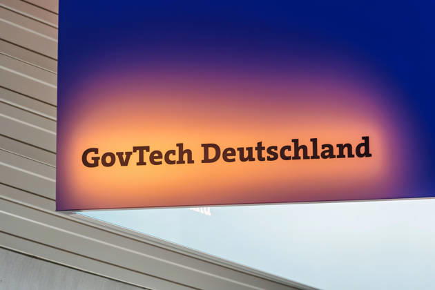 Berlin, 13.10.2026: Der beleuchtete Schriftzug GovTech Deutschland an einem Deckenaufbau auf der Smart Country Convention in der Halle hub27. Unter dem Begriff GovTech werden Technologien und junge Unternehmen zusammengefasst, die Lösungen für Staat und öffentliche Verwaltung entwickeln. Die Smart Country Convention (SCCON) ist die Kongressmesse für die Digitalisierung des öffentlichen Sektors und wird vom Digitalverband Bitkom gemeinsam mit der Messe Berlin veranstaltet. Vom 13. bis 15. Oktober 2026 treffen sich in der Halle hub27 Vertreter aus Bund, Ländern und Kommunen mit Unternehmen der Digitalwirtschaft, um über digitale Verwaltung, Smart City und digitale Souveränität zu diskutieren. Schriftzug GovTech Deutschland auf