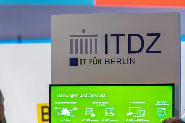 Berlin, 13.10.2026: Der Messestand des ITDZ Berlin mit dem Slogan IT für Berlin auf der Smart Country Convention; ein Bildschirm zeigt Kennzahlen des Unternehmens, darunter mehr als 14.000 betriebene Server und über 19.300 IT-Arbeitsplätze. Das IT-Dienstleistungszentrum Berlin ist als Anstalt öffentlichen Rechts der zentrale IT-Dienstleister der Berliner Verwaltung. Die Smart Country Convention (SCCON) ist die Kongressmesse für die Digitalisierung des öffentlichen Sektors und wird vom Digitalverband Bitkom gemeinsam mit der Messe Berlin veranstaltet. Vom 13. bis 15. Oktober 2026 treffen sich auf dem Berliner Messegelände Vertreter aus Bund, Ländern und Kommunen mit Unternehmen der Digitalwirtschaft, um über digitale Verwaltun