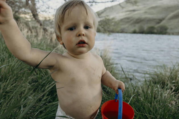 Cute toddler boy holding a red bucket by a river The Dalles, Oregon, United States CR_XICZ261001B9-2131791-01 ,model released, Symbolfoto ,property released