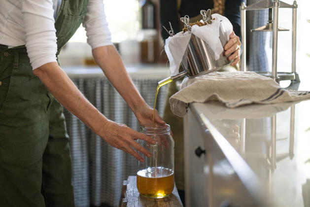 Woman filtering freshly pressed oil into a large glass jar Woodlawn, New South Wales, Australia R_MGTP261007-2138040-01 ,model released, Symbolfoto ,property released