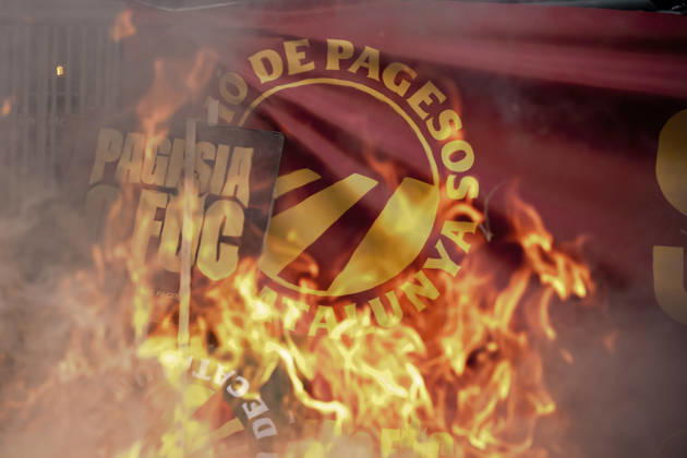 October 14, 2026, Barcelona, Catalonia, Spain: A sign reading Pagesia o foc ( Farming or Fire ) is seen through flames outside the Catalan Agriculture Ministry during a farmers protest in Barcelona demanding fair prices, lower fuel costs and protection against unfair competition from imports. Barcelona Spain  - ZUMAo105 20261014_fap_o105_011 Copyright: xMatthiasxOesterlex