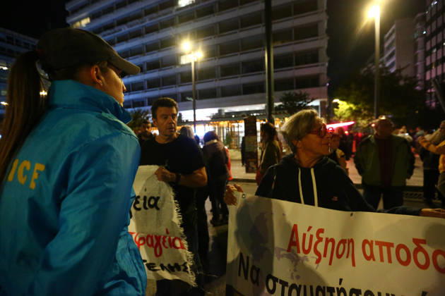 October 15, 2026, Athens, Attica, GREECE: A police officer stands alongside demonstrators holding banners calling for improvements in wages and pensions. Athens GREECE  - ZUMAx103 20261015_zip_x103_022 Copyright: xHarrisxXanthopoulosx