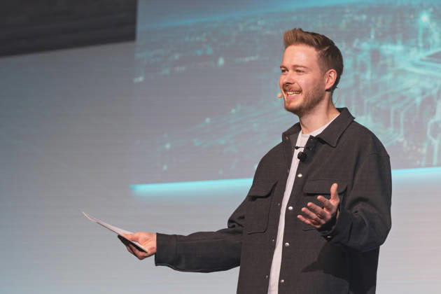 Berlin, October 16, 2026 Host Sascha Müller, in high spirits and holding cue cards and a headset microphone, welcomes the audience o