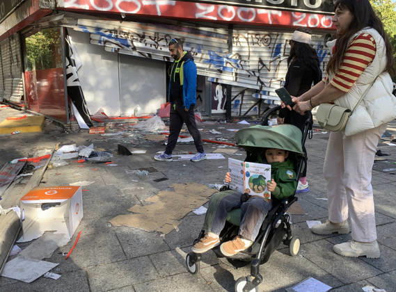 People walk in front of a vandalised shop near Republique Square in Paris, on Sunday, October 18, 2026. Residents awoke to scenes of widespread damage with shopfronts shattered, burnt out cars, charred bikes, and piles of glass and debris on the pavements of the French capital a day after riots erupted during protests against rising fuel prices, the cost of living and deteriorating public services, including schools.  PAR20261018112 MAYAxVIDON-WHITE