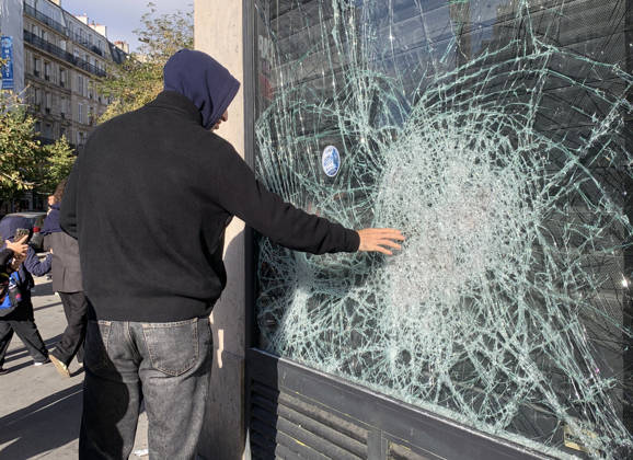 A man feels a shattered shop window near Republique Square in Paris, on Sunday, October 18, 2026. Residents awoke to scenes of widespread damage with shopfronts shattered, burnt out cars, charred bikes, and piles of glass and debris on the pavements of the French capital a day after riots erupted during protests against rising fuel prices, the cost of living and deteriorating public services, including schools.  PAR20261018115 MAYAxVIDON-WHITE
