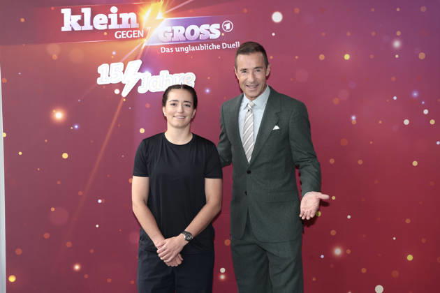 Mathilde Gremaud and Kai Pflaume at the photo call for the 15th-anniversary episode of the ARD show *Klein gegen Gross: Das unglaubliche Duell* on October 18, 2026, in Berlin. Mathilde Gremaud and Kai Pflaume attend the photo call for the 15th-anniversary episode of the ARD show *Klein gegen Gross: Das unglaubliche Du