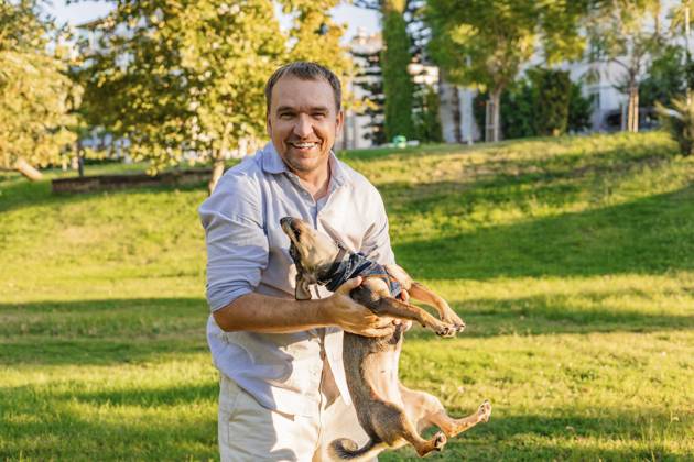 Ein lächelnder Mann wiegt seinen kleinen Hund in einem sonnigen Park A smiling man cradles his small dog in a sunny park Copyright: imageBROKER AlinaxKandybka ibxayk19658900.jpg ,model released, Symbolfoto ,property released