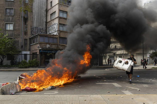October 19, 2026, Santiago, Chile: A man walks past a burning barricade during the demonstration. In the center of the capital of Chile, different incidents took place between demonstrators and the police. The riots were carried out during the commemoration of the 7 years after the social outcast that happened on October 18, 2019. Santiago Chile  - ZUMAs197 20261019_aaa_s197_002 Copyright: xSebastianxNancox