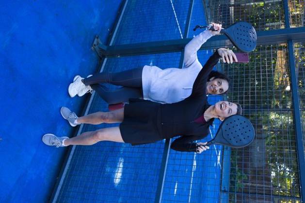 Diverse female friends posing for selfie on blue padel court holding black paddles, pink smartphone, model released, property released, 09.06.2026 06:00:00, 18050230 Copyright: xIDS-261019_1xcreatorid:x0x 18050230