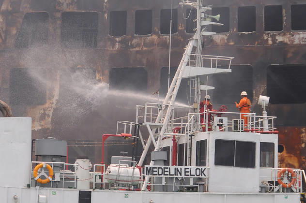Efforts are underway to extinguish a fire that broke out on a passenger ferry in Indonesia s Cilegon PELABUHAN MERAK, CILEGON, INDONESIA - OCTOBER 21: Fireboats take turns spraying water onto the passenger ferry KMP Batumandi to cool down the vessel after it caught fire while preparing to dock off Merak Port in Cilegon, Banten, Indonesia on Wednesday, October 21, 2026. The vessel caught fire on Tuesday, October 20, and rescue operations remain underway as the ship continues to emit smoke. Water is continuously sprayed to cool the vehicle deck containing numerous cars, motorcycles, buses, and trucks, while authorities confirm no fatalities have been reported. Dasril Roszandi Anadolu Pelabuhan Merak Indonesia. Editorial use only. Please get Copyright: x2026xAnadoluxDasrilxRoszandix