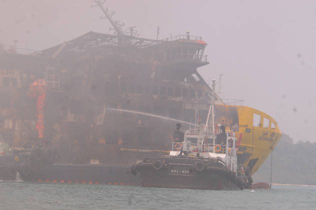Efforts are underway to extinguish a fire that broke out on a passenger ferry in Indonesia s Cilegon PELABUHAN MERAK, CILEGON, INDONESIA - OCTOBER 21: Fireboats take turns spraying water onto the passenger ferry KMP Batumandi to cool down the vessel after it caught fire while preparing to dock off Merak Port in Cilegon, Banten, Indonesia on Wednesday, October 21, 2026. The vessel caught fire on Tuesday, October 20, and rescue operations remain underway as the ship continues to emit smoke. Water is continuously sprayed to cool the vehicle deck containing numerous cars, motorcycles, buses, and trucks, while authorities confirm no fatalities have been reported. Dasril Roszandi Anadolu Pelabuhan Merak Indonesia. Editorial use only. Please get Copyright: x2026xAnadoluxDasrilxRoszandix
