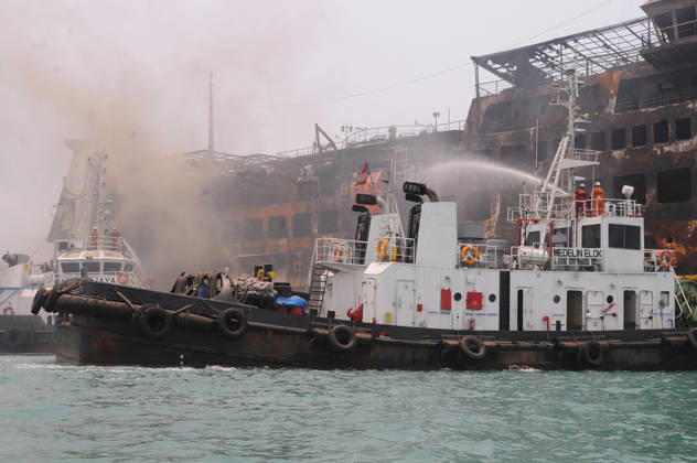 Efforts are underway to extinguish a fire that broke out on a passenger ferry in Indonesia s Cilegon PELABUHAN MERAK, CILEGON, INDONESIA - OCTOBER 21: Fireboats take turns spraying water onto the passenger ferry KMP Batumandi to cool down the vessel after it caught fire while preparing to dock off Merak Port in Cilegon, Banten, Indonesia on Wednesday, October 21, 2026. The vessel caught fire on Tuesday, October 20, and rescue operations remain underway as the ship continues to emit smoke. Water is continuously sprayed to cool the vehicle deck containing numerous cars, motorcycles, buses, and trucks, while authorities confirm no fatalities have been reported. Dasril Roszandi Anadolu Pelabuhan Merak Indonesia. Editorial use only. Please get Copyright: x2026xAnadoluxDasrilxRoszandix
