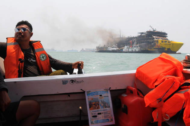 Efforts are underway to extinguish a fire that broke out on a passenger ferry in Indonesia s Cilegon PELABUHAN MERAK, CILEGON, INDONESIA - OCTOBER 21: Fireboats take turns spraying water onto the passenger ferry KMP Batumandi to cool down the vessel after it caught fire while preparing to dock off Merak Port in Cilegon, Banten, Indonesia on Wednesday, October 21, 2026. The vessel caught fire on Tuesday, October 20, and rescue operations remain underway as the ship continues to emit smoke. Water is continuously sprayed to cool the vehicle deck containing numerous cars, motorcycles, buses, and trucks, while authorities confirm no fatalities have been reported. Dasril Roszandi Anadolu Pelabuhan Merak Indonesia. Editorial use only. Please get Copyright: x2026xAnadoluxDasrilxRoszandix