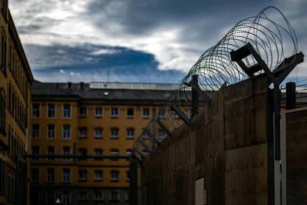October 21, 2026, Germany, Saxony, Bautzen: A surveillance camera and a streetlight in front of the historic buildings of the Bautzen Correctional Facility in Saxony. The prison complex is secured by walls and security fences.