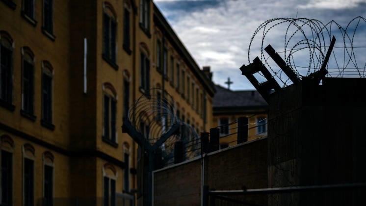 October 21, 2026, Germany, Saxony, Bautzen: A surveillance camera and a streetlight in front of the historic buildings of the Bautzen Correctional Facility in Saxony. The prison complex is secured by walls and security fences.