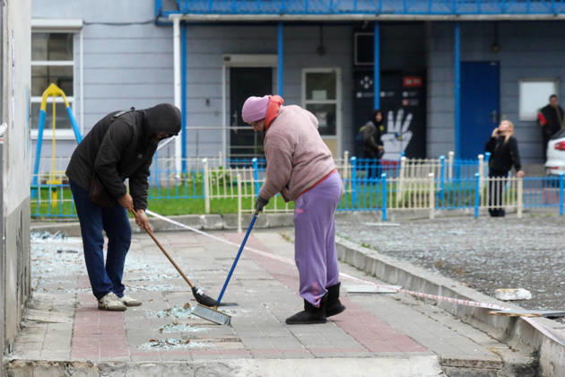 People remove debris and glass shards outside an apartment block in the Sviatoshynskyi district damaged by a Russian drone strike, Kyiv, Ukraine, October 21, 2026. The drone hit the building’s 20th floor, sparking a fire. Two people were killed in the attack. (Photo by Volodymyr Tarasov Ukrinform) Russian drone hits 24-storey apartment block in Kyiv  Copyright: xVolodymyrxTarasovx