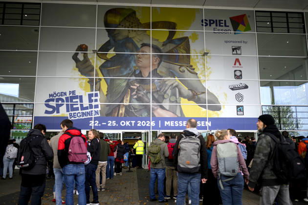 Visitors wait in front of the East Entrance; a rush of people; behind them, the SPIEL 26 logo; on October 22, 2026, at the SPIEL Essen trade show, held from October 22–25, 2026, in Essen, Germany, at the Grugahalle