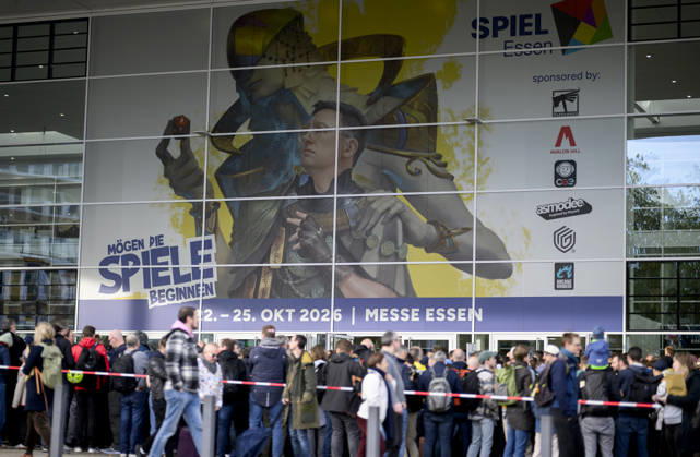 Visitors wait in front of the East Entrance; a rush of people; behind them, the SPIEL 26 logo; on October 22, 2026, at the SPIEL Essen trade show, held from October 22–25, 2026, in Essen, Germany, at the Grugahalle