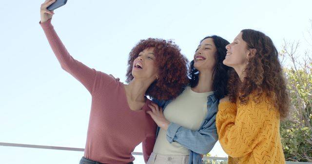 Diverse female friends posing for selfie on balcony holding phone by railing wearing denim jacket, model released, property released, Cape Town, South Africa, 02.09.2025 06:00:00, 10921366 Copyright: xIPW-260215_1xcreatorid:x415x 10921366