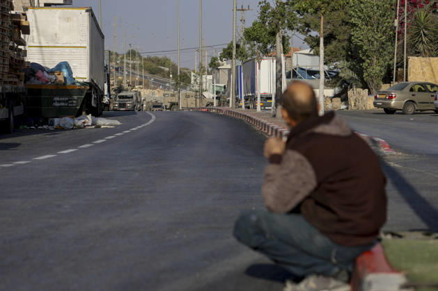 Hebron West Bank Shooting Attack A man crouches on the street as Israeli military vehicles stand guard at the entrance to Farsh al-Hawa near Hebron, in the occupied West Bank on October 23, 2026. Journalists were targeted and the area was declared a closed military zone following a Palestinian shooting attack targeting an Israeli military checkpoint at the entrance to Farsh al-Hawa in Hebron. Hebron West Bank Palestinian Territories Copyright: xMosabxShawerx