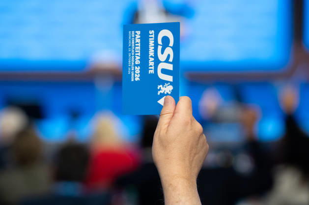 Munich, Bavaria, Germany October 23, 2026: The 2026 convention of the CSU (Christian Social Union) at the Munich Trade Fair Center. A hand holds a voting card aloft