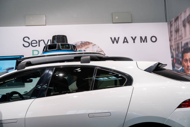 Munich, Bavaria, Germany October 23, 2026: The 2026 convention of the CSU (Christian Social Union) party at the Munich Trade Fair Center. Background image: a close-up of a white Jaguar I-PACE equipped with autonomous driving technology from the U.S. company Waymo. The electric vehicle is equipped with cameras, LiDAR, and radar sensors for AI-assisted detection of its surroundings and is designed for use as a self-driving robotaxi