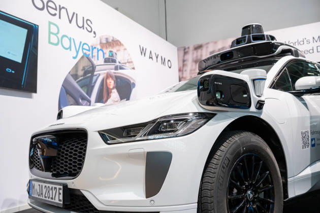 Munich, Bavaria, Germany October 23, 2026: The 2026 convention of the CSU (Christian Social Union) party at the Munich Trade Fair Center. Background image: a close-up of a white Jaguar I-PACE equipped with autonomous driving technology from the U.S. company Waymo. The electric vehicle is equipped with cameras, LiDAR, and radar sensors for AI-assisted detection of its surroundings and is designed for use as a self-driving robotaxi