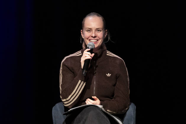 Poetry artist and author Clara LOESEL LÖSEL laughing during her reading, a preview event for her new book *Ich dachte, sowas fühle nur ich* (I Thought I Was the Only One Who Felt That Way), seated with a microphone; single frame, single photo, at the Theater am Tanzbrunnen, Cologne, on October 23, 2026