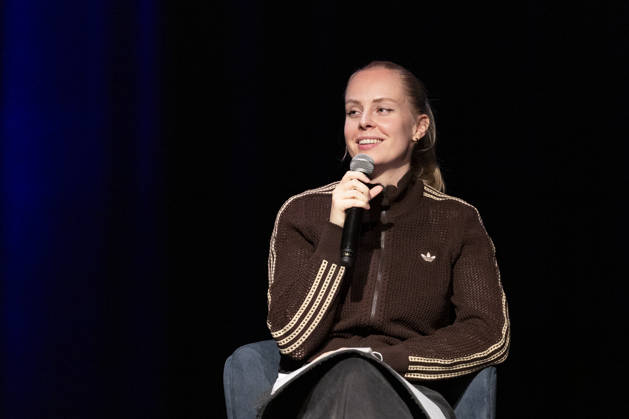 Poetry artist and author Clara LOESEL LÖSEL laughing during her reading, a preview show for her new book *Ich dachte, sowas fühle nur ich* (I Thought I Was the Only One Who Felt That Way), seated with a microphone; single frame, single photo, at the Theater am Tanzbrunnen, Cologne, on October 23, 2026