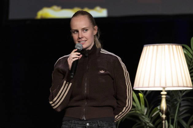 Poetry artist and author Clara LOESEL LÖSEL speaks intently during her reading—a preview of her new book, *Ich dachte, sowas fühle nur ich*—standing with a microphone, in a single frame, a single photograph, at the Theater am Tanzbrunnen, Cologne, on October 23, 2026