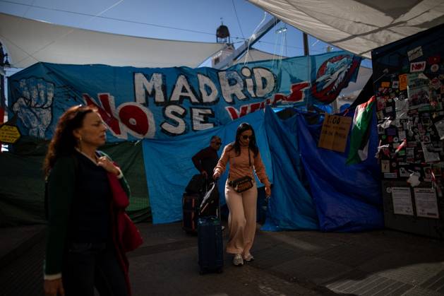 October 23, 2026, Madrid, Spain: A couple walks with suitcases in front of tents set up at Puerta del Sol..Tents remain set up by housing rights activists, who organized the occupation of the square in response to the eviction of MaricarmenÃ¢â‚¬a woman in her eightiesÃ¢â‚¬from her home, carried out by a real estate investment fund. Madrid Spain  - ZUMAs197 20261023_aaa_s197_149 Copyright: xDavidxCanalesx