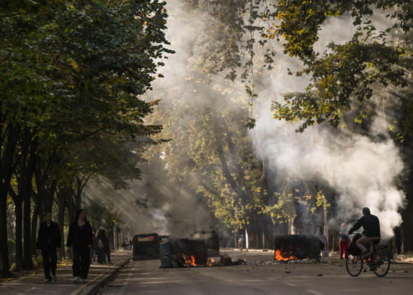 Mass Anti-Government National Protest in Tirana TIRANA, ALBANIA - OCTOBER 24: Public trash bins burn on a tree-lined street filling the air with heavy smoke as citizens and a cyclist pass by on October 24, 2026, in Tirana, Albania. Unrest and physical confrontations erupt in Tirana city center as demonstrators and riot police clash during a massive nationwide protest, turning the capital s main avenue into a major flashpoint as chaotic skirmishes broke out between security forces and factions of the crowd. Artur Widak Anadolu Tirana Albania. Editorial use only. Please get in touch for any other usage.  Copyright: x2026xAnadoluxArturxWidakx