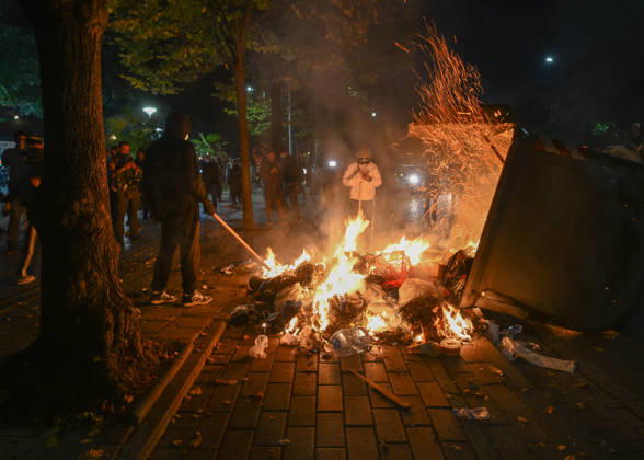 Mass Anti-Government National Protest in Tirana TIRANA, ALBANIA - OCTOBER 24: Masked individuals use a long pole to stoke a large dumpster fire burning on a city sidewalk at night on October 24, 2026, in Tirana, Albania. Unrest and physical confrontations erupt in Tirana city center as demonstrators and riot police clash during a massive nationwide protest, turning the capital s main avenue into a major flashpoint as chaotic skirmishes broke out between security forces and factions of the crowd. Artur Widak Anadolu Tirana Albania. Editorial use only. Please get in touch for any other usage.  Copyright: x2026xAnadoluxArturxWidakx