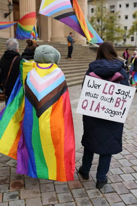 Protesters stand with a rainbow flag and a sign reading If you say LG, you must also say BTQIA at the Alter Markt during Bike Pride in Potsdam, October 24, 2026. Bike Pride Potsdam