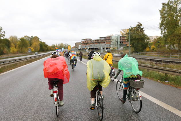 Protesters wearing colorful rain capes ride down Nuthestraße heading out of town during Bike Pride in Potsdam, October 24, 2026 Bike Pride Potsdam
