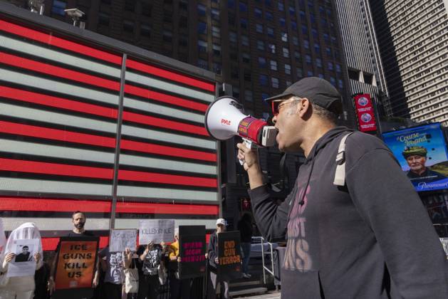 October 25, 2026, New York, New York, USA: JAY W. WALKER, President of Gays Against Guns leads chants at a demonstration under the Times Square US Army Recruiting Station LED American flag to denounce U.S. Immigration and Customs Enforcement (ICE) and President Trump s immigrant detention and mass deportation policies. People dressed in white shrouds are Human Beings, memorializing people killed by gun violence from Federal immigration agents by holding signs with their images and names. Protesters hold signs that read ICE GUNS KILL US KILLED BY ICE DISARM BOGUS PATRIOTS END GUN TERROR. New York USA  - ZUMAr174 20261025_znp_r174_004 Copyright: xGinaxMxRandazzox