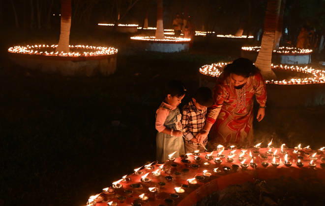 October 25, 2026, Mumbai, Maharashtra, India: A woman (R) helps her children to light earthen lamp on the occasion of Sharad Purnima (full moon) celebration in Mumbai. Sharad Purnima, also known as the Full Moon Festival, marks the end of the monsoon season. devotees observe fasting and meditate on the full moon night, Goddess Lakshmi, the deity of wealth, is worshipped on this day as it is believed to be her birthday. praying to her is said to bring good luck and prosperity in the life of devotees. Mumbai India  - ZUMAs197 20261025_aab_s197_019 Copyright: xAshishxVaishnavx