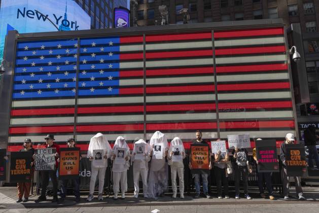 October 25, 2026, New York, New York, USA: Demonstrators with the anti-gun violence organization Gays Against Guns protest under the Times Square US Army Recruiting Station LED American flag to denounce U.S. Immigration and Customs Enforcement (ICE) and President Trump s immigrant detention and mass deportation policies. Protesters hold signs that read END GUN TERROR ICE IS A HATE CRIME ICE GUNS KILL US DISARM BOGUS PATRIOTS. People dressed in white shrouds are Human Beings, memorializing people killed by gun violence from Federal immigration agents by holding signs with their images and names. New York USA - ZUMAr174 20261025_znp_r174_006 Copyright: xGinaxMxRandazzox