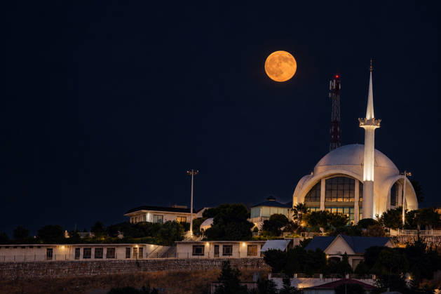 October 26, 2026, Erbil, Kurdistan Region, Iraq: A glowing full moon illuminates the night sky behind a modern illuminated mosque in Erbil Iraq on October 26 2026 Erbil Iraq  - ZUMAr205 20261026_zip_r205_001 Copyright: xSaburxRashidx