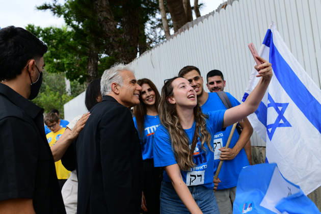 Tel Aviv Israel Parliamentary Elections Israeli opposition leader Yair Lapid poses as a supporter in a blue campaign shirt takes a selfie beside an Israeli flag in Tel Aviv, Israel on October 27, 2026. Israelis vote in parliamentary elections to choose members of the 26th Knesset. Tel Aviv Tel Aviv Israel Copyright: xTomerxNeubergx