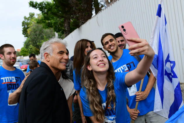 Tel Aviv Israel Parliamentary Elections Israeli opposition leader Yair Lapid poses as a supporter in a blue campaign shirt takes a selfie beside an Israeli flag in Tel Aviv, Israel on October 27, 2026. Israelis vote in parliamentary elections to choose members of the 26th Knesset. Tel Aviv Tel Aviv Israel Copyright: xTomerxNeubergx