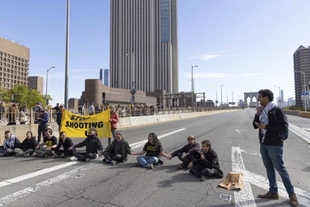 October 28, 2026, New York, New York, USA: Anti-ICE (U.S. Immigration and Customs Enforcement) demonstrators sit in the roadway on the Brooklyn Bridge with a banner that reads STOP SHOOTING US protesting the continued detainment of O. Belgal, who was shot by federal agents in the Bronx with his 5-yr-old son in the car. The demonstration stopped Brooklyn bound traffic and results in arrests by NYPD. Protesters call for ICE out of New York. New York USA - ZUMAr174 20261028_znp_r174_012 Copyright: xGinaxMxRandazzox