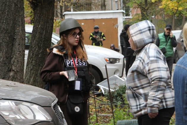 A journalist in a helmet and a ballistic vest talks to a woman outside an apartment block on Oleksandra Polia Avenue damaged by a Russian drone strike in Dnipro, Ukraine, on October 30, 2026. The Russian attack damaged at least five residential high-rise buildings and a school. More than 300 windows were shattered in the strike. (Photo by Mykola Miakshykov Ukrinform) Russian attack damages residential buildings and school in Dnipro  Copyright: xMykolaxMiakshykovx