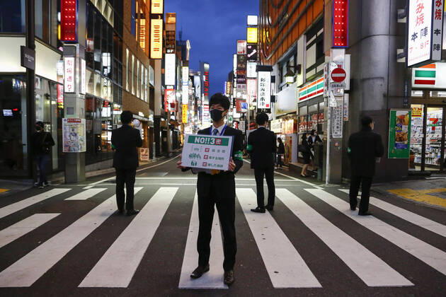 Coronavirus in Japan, Helfer machen in Tokio mit Plakaten auf Kontaktverbot aufmerksam